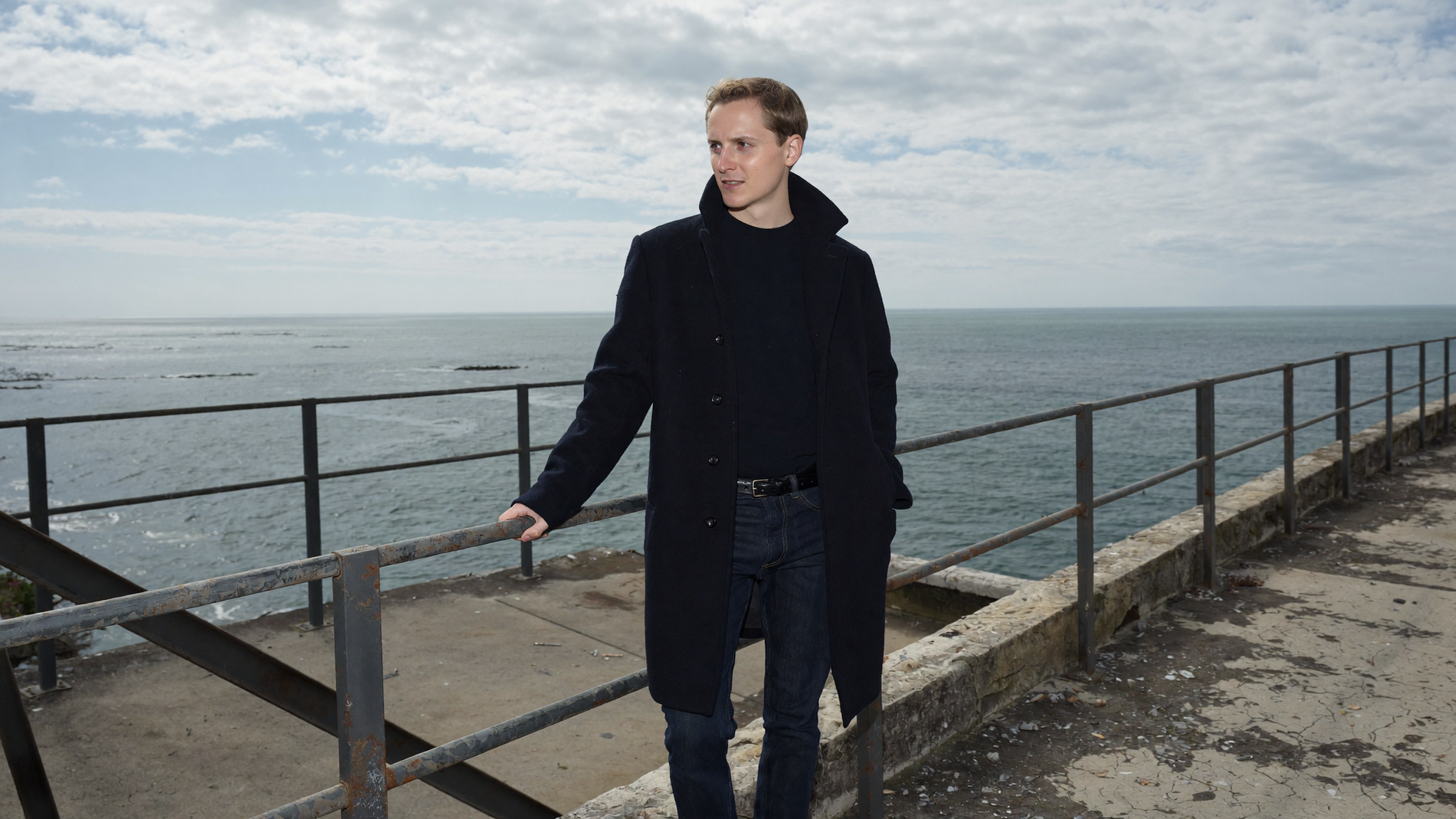 Uncaffed Founder standing on a pier by the ocean with a cloudy sky.